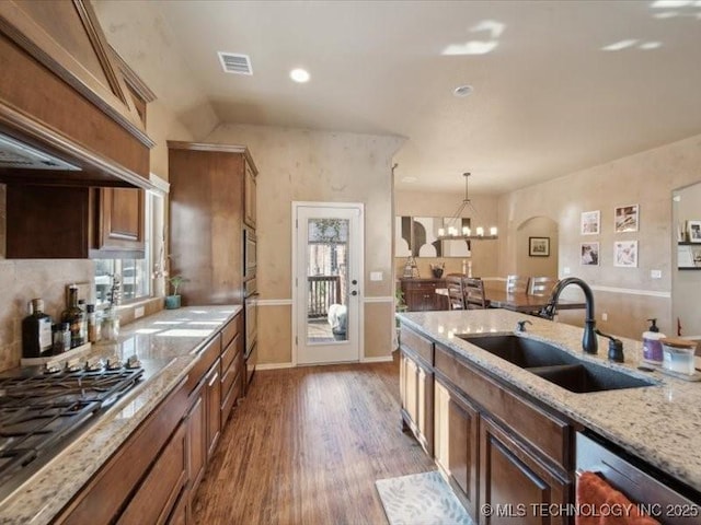 kitchen featuring pendant lighting, sink, appliances with stainless steel finishes, light stone countertops, and dark hardwood / wood-style flooring