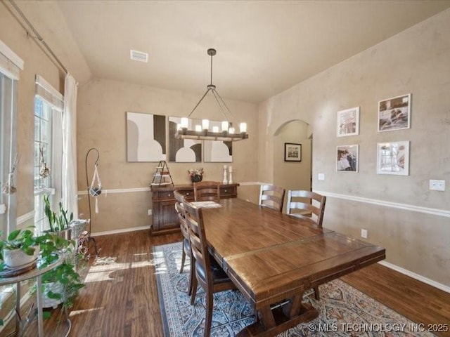 dining area with dark hardwood / wood-style flooring, vaulted ceiling, and a chandelier