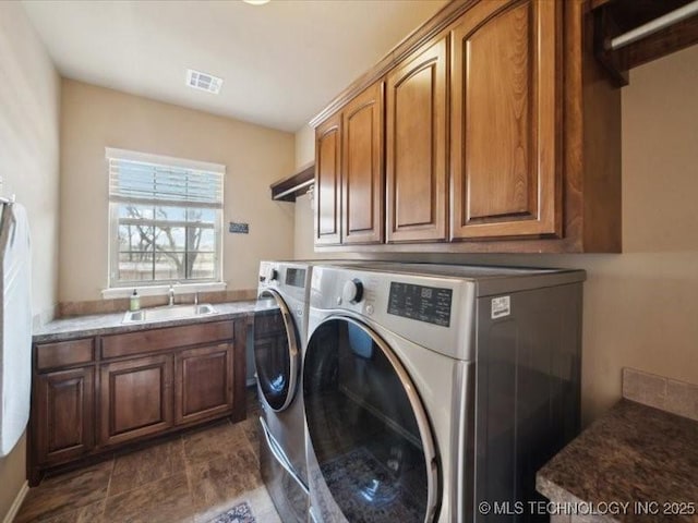 clothes washing area with cabinets, sink, and washer and dryer