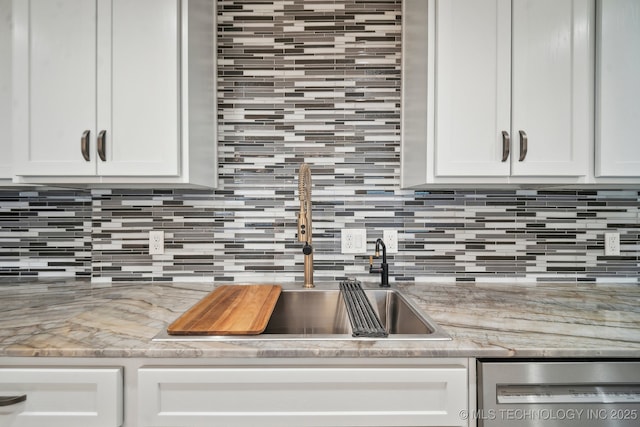 kitchen with white cabinetry, stainless steel dishwasher, light stone counters, and decorative backsplash