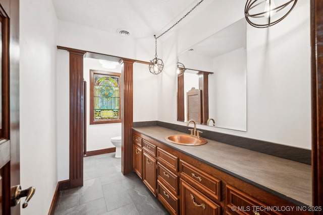 bathroom with decorative columns, vanity, and toilet