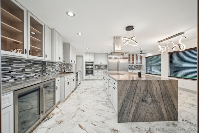 kitchen with a spacious island, light stone counters, appliances with stainless steel finishes, island exhaust hood, and white cabinets