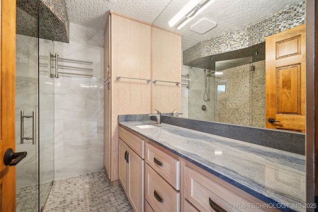 bathroom with vanity, an enclosed shower, and a textured ceiling