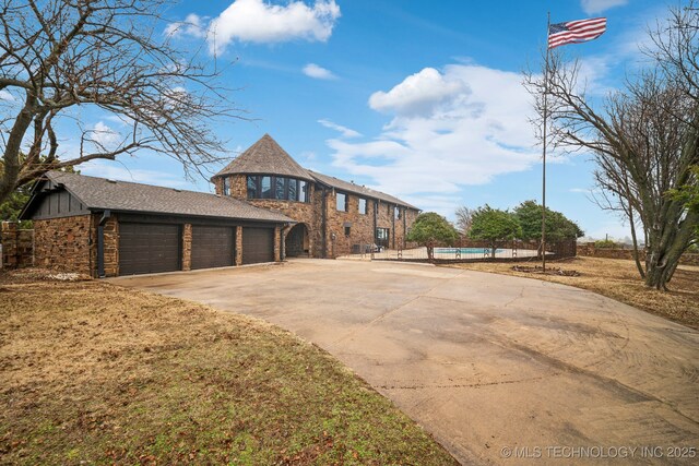 6642 E 60th Pl, Tulsa, OK 74145 - view of front of house with stone siding, driveway, and board and batten siding
