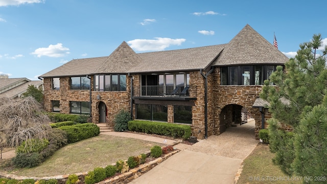 6642 E 60th Pl, Tulsa, OK 74145 - english style home with a balcony, stone siding, concrete driveway, and roof with shingles