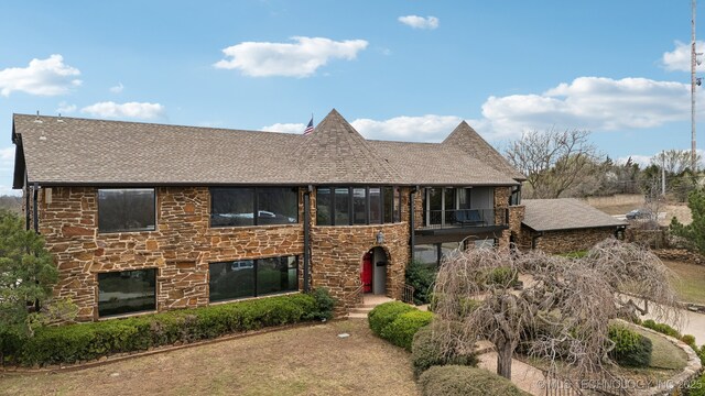 6642 E 60th Pl, Tulsa, OK 74145 - view of front of home with roof with shingles, stone siding, and a balcony