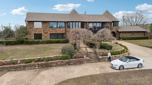 6642 E 60th Pl, Tulsa, OK 74145 - view of front facade featuring a balcony, stone siding, concrete driveway, a front lawn, and stairs