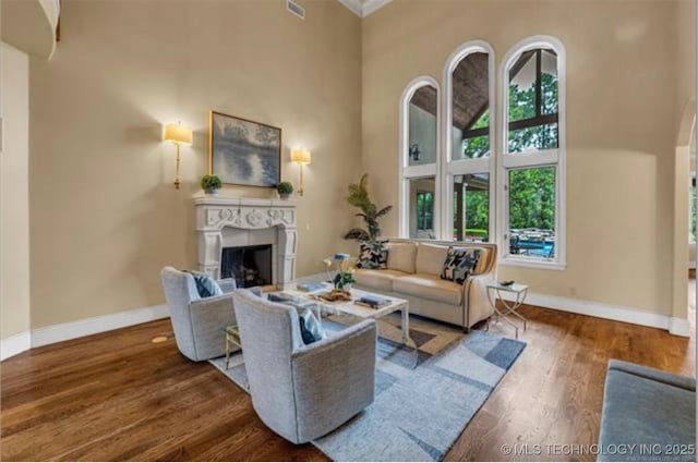 living room with hardwood / wood-style flooring, a fireplace, and a high ceiling