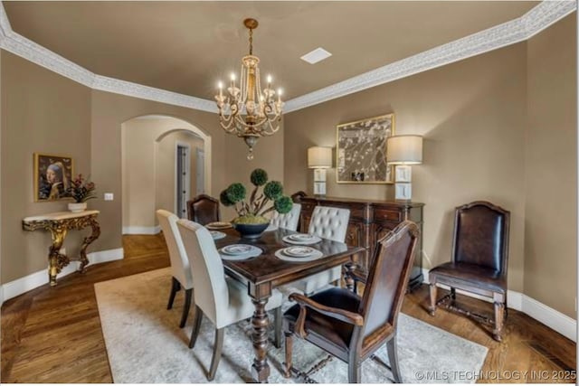 dining area featuring ornamental molding, hardwood / wood-style floors, and an inviting chandelier