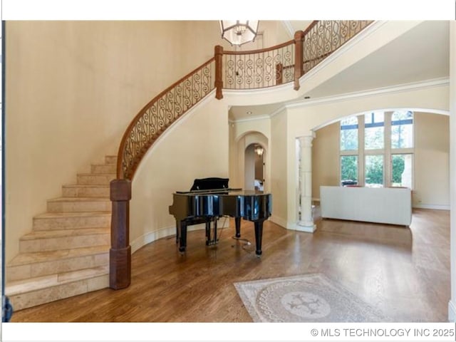 entryway featuring a high ceiling, ornamental molding, and hardwood / wood-style flooring