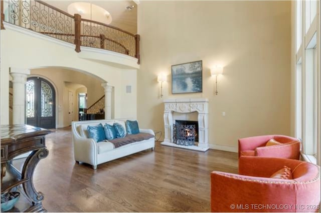 living room featuring french doors, wood-type flooring, a high ceiling, and ornate columns