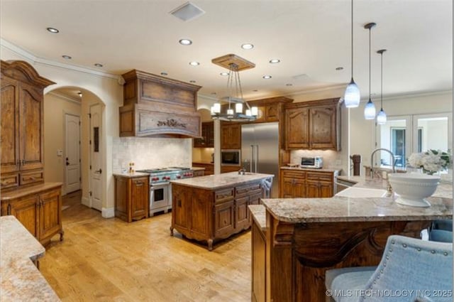 kitchen with pendant lighting, premium appliances, sink, and a large island with sink