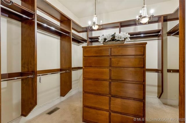 walk in closet with light carpet and a notable chandelier