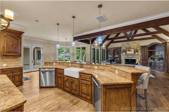 kitchen with decorative light fixtures, lofted ceiling with beams, sink, stainless steel dishwasher, and a spacious island