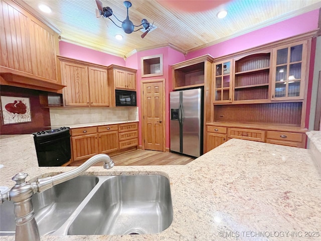 kitchen with tasteful backsplash, sink, black appliances, light stone countertops, and light wood-type flooring