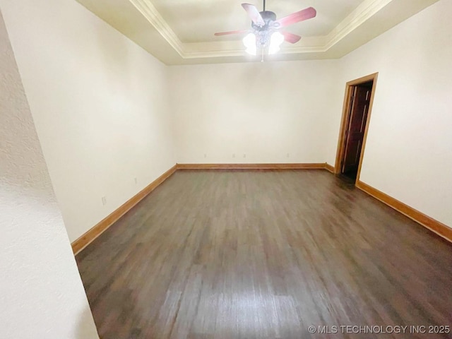 spare room featuring a raised ceiling, ornamental molding, and dark hardwood / wood-style flooring