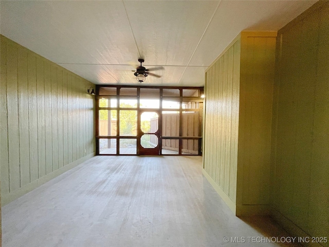 unfurnished room featuring wood walls, ceiling fan, and light hardwood / wood-style flooring