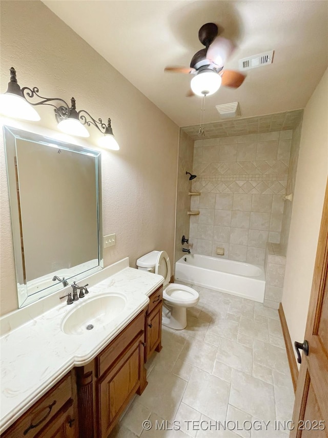 full bathroom featuring ceiling fan, vanity, toilet, and tiled shower / bath combo