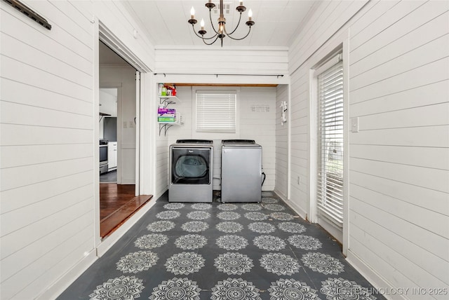 clothes washing area with washing machine and dryer and a chandelier