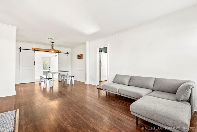 living room featuring crown molding, a barn door, and dark hardwood / wood-style floors