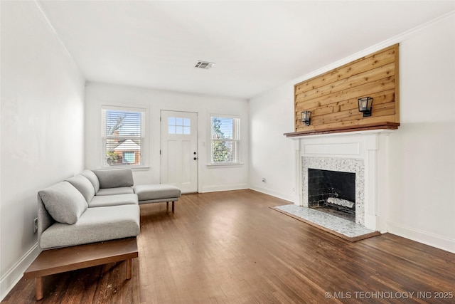 living room with crown molding, wood-type flooring, and a tiled fireplace