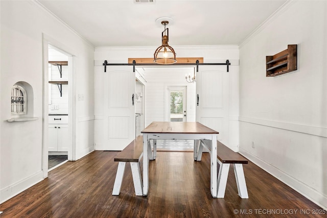 dining area featuring dark hardwood / wood-style flooring, crown molding, and a barn door