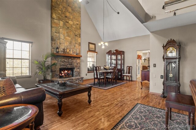 living room featuring wood-type flooring, high vaulted ceiling, an inviting chandelier, and a fireplace