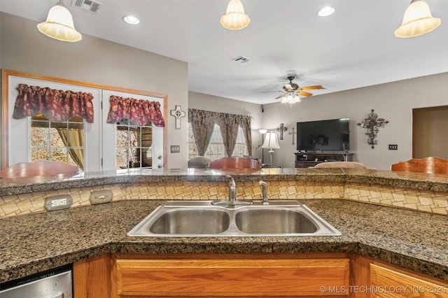 kitchen featuring hanging light fixtures, dishwasher, and sink