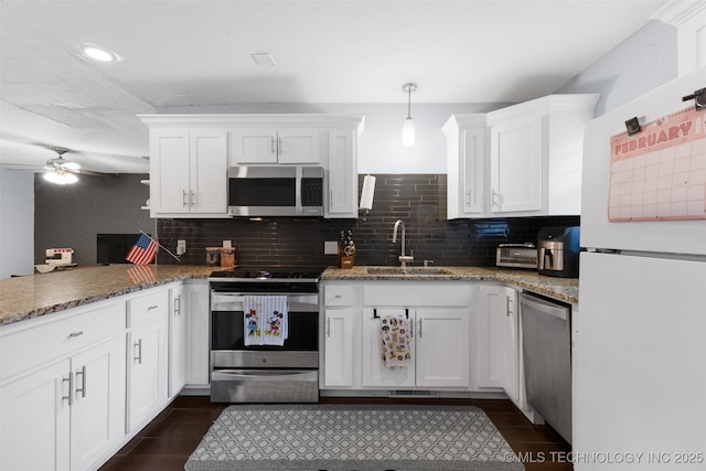 kitchen featuring hanging light fixtures, stainless steel appliances, white cabinets, and stone counters