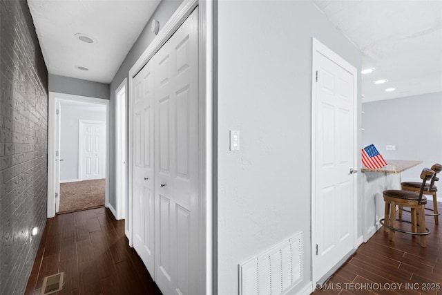 hallway with dark hardwood / wood-style flooring and brick wall