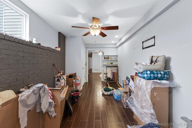 interior space with ceiling fan, brick wall, and dark hardwood / wood-style flooring