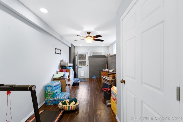 interior space with an AC wall unit, dark hardwood / wood-style floors, and ceiling fan