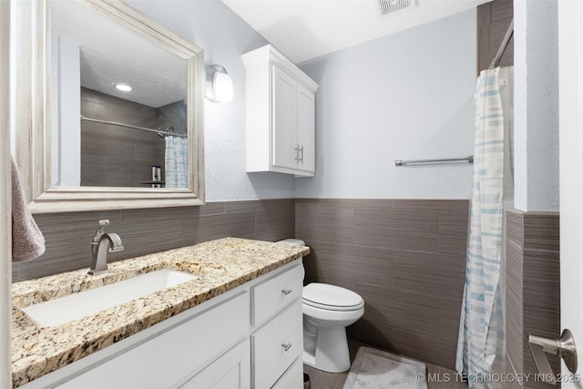 bathroom featuring vanity, tile walls, curtained shower, and toilet