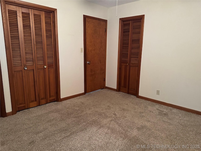 unfurnished bedroom featuring two closets and light carpet