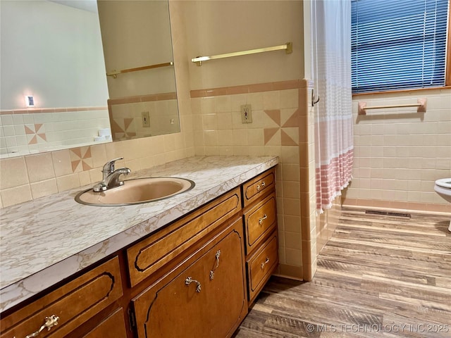 bathroom with vanity, hardwood / wood-style floors, and tile walls