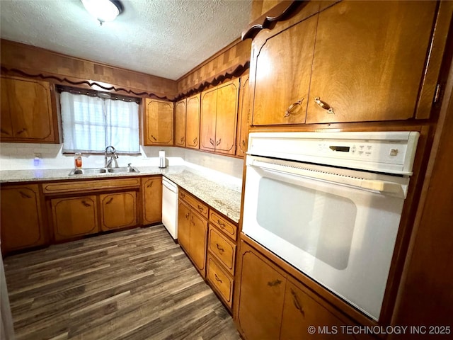 kitchen with dark hardwood / wood-style flooring, sink, white appliances, and a textured ceiling