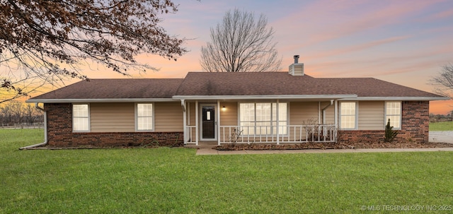 ranch-style house featuring a porch and a lawn