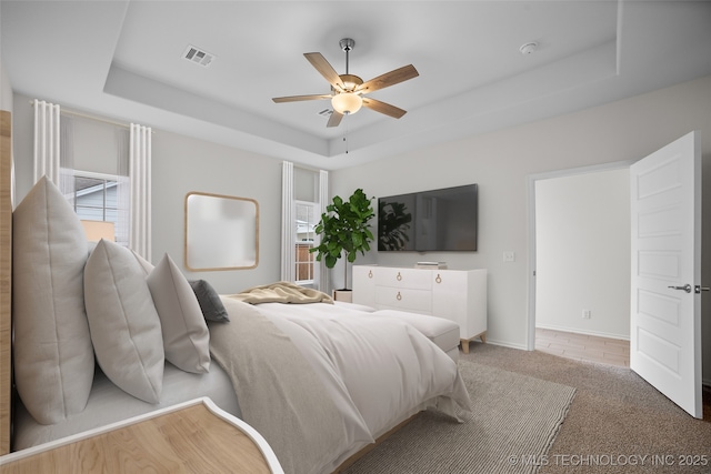 bedroom featuring a tray ceiling, carpet floors, and ceiling fan