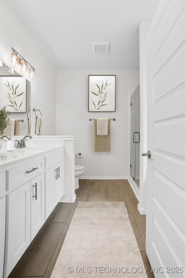 bathroom with vanity, toilet, and a shower with shower door