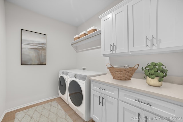 clothes washing area featuring independent washer and dryer, cabinets, and light hardwood / wood-style floors