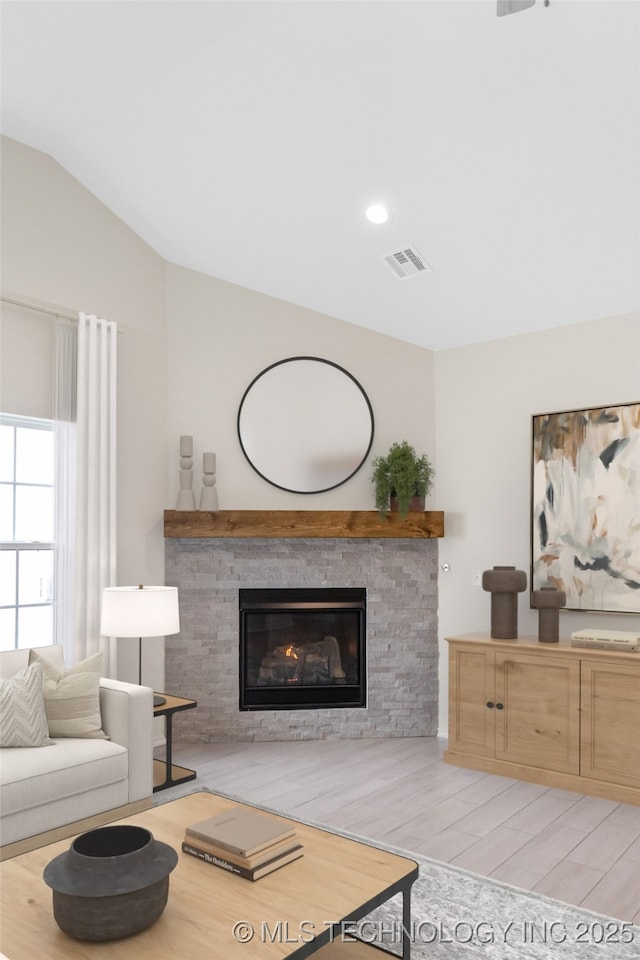 living room featuring a fireplace, vaulted ceiling, and light wood-type flooring