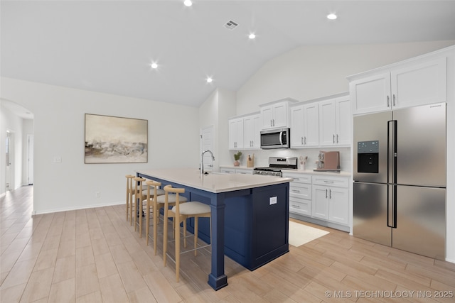 kitchen featuring white cabinetry, a kitchen bar, an island with sink, and appliances with stainless steel finishes