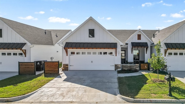 modern inspired farmhouse with a garage, a front yard, and covered porch