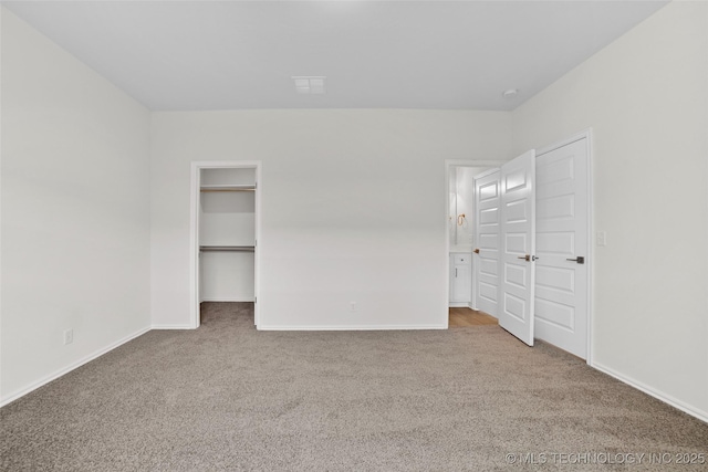 unfurnished bedroom with a walk in closet and carpet floors