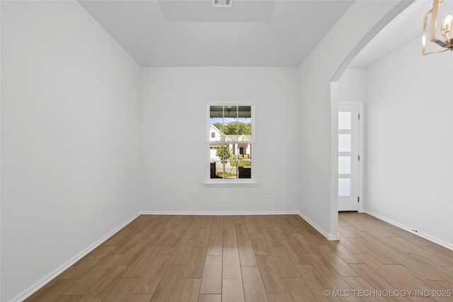 spare room with a notable chandelier and light hardwood / wood-style flooring