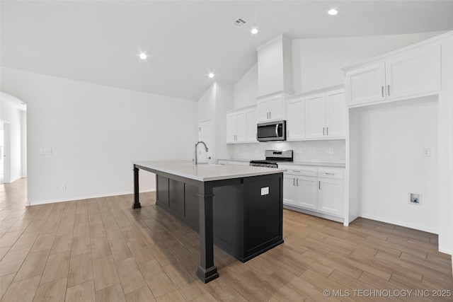 kitchen featuring a breakfast bar, a kitchen island with sink, stainless steel appliances, light hardwood / wood-style floors, and white cabinets