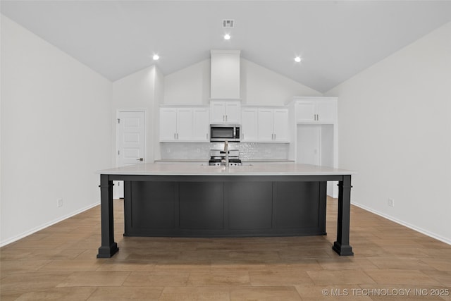 kitchen with appliances with stainless steel finishes, a kitchen breakfast bar, an island with sink, and white cabinets