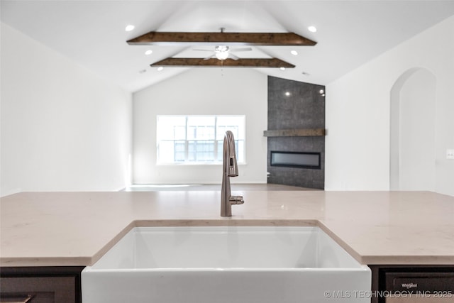 kitchen with sink, vaulted ceiling with beams, and a large fireplace