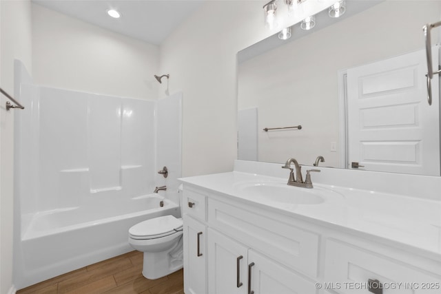 full bathroom with  shower combination, toilet, hardwood / wood-style floors, and vanity