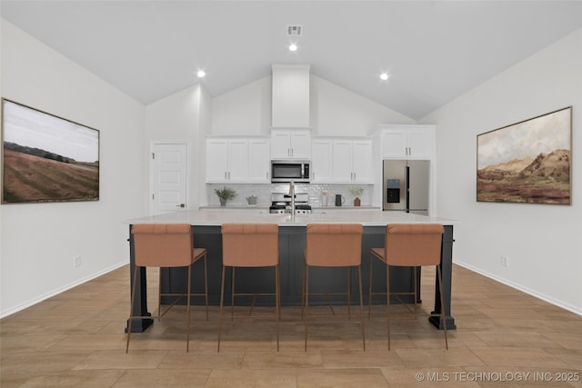 1941 W Huntsville Pl, Broken Arrow, OK 74011 - kitchen with stainless steel appliances, a large island with sink, white cabinetry, backsplash, and high vaulted ceiling